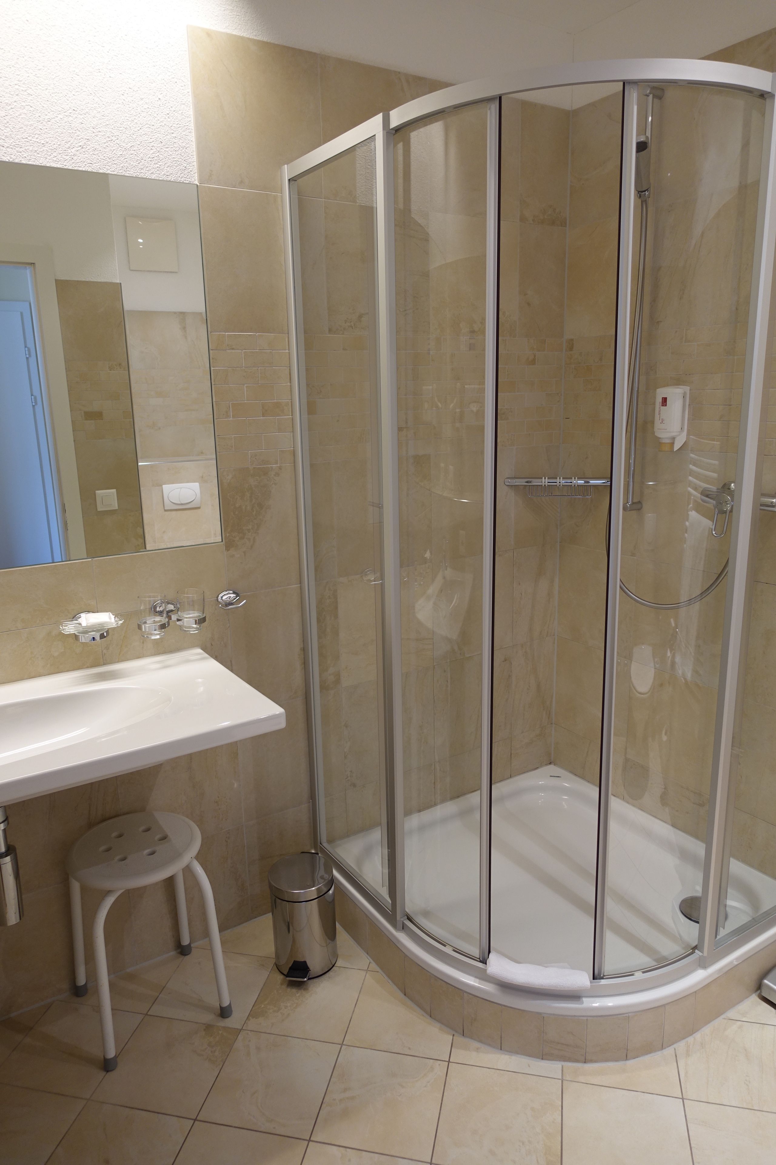Une salle de bain avec une douche à parois de verre, un lavabo et un miroir.