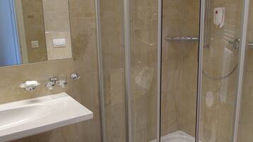 Une salle de bain avec une douche à parois de verre, un lavabo et un miroir.
