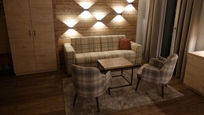 A cozy living room with a plaid sofa, two plaid armchairs, a wooden coffee table, and a wooden wardrobe. - Hotel Schweizerhof Engelberg (Engelberg)