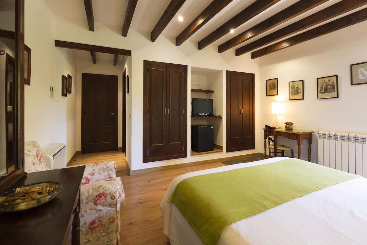 A hotel room with a bed, a desk, a chair, a television, and a small refrigerator.