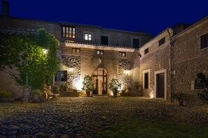 A courtyard with a stone floor, a bench, and potted plants. - Agroturisme Sa Torre (Santa Eugenia)