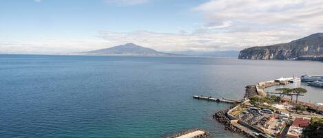 A coastal town with a pier, a mountain in the background, and a clear sky.