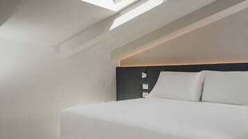 A modern bedroom with a skylight, a bed, and a dark headboard.