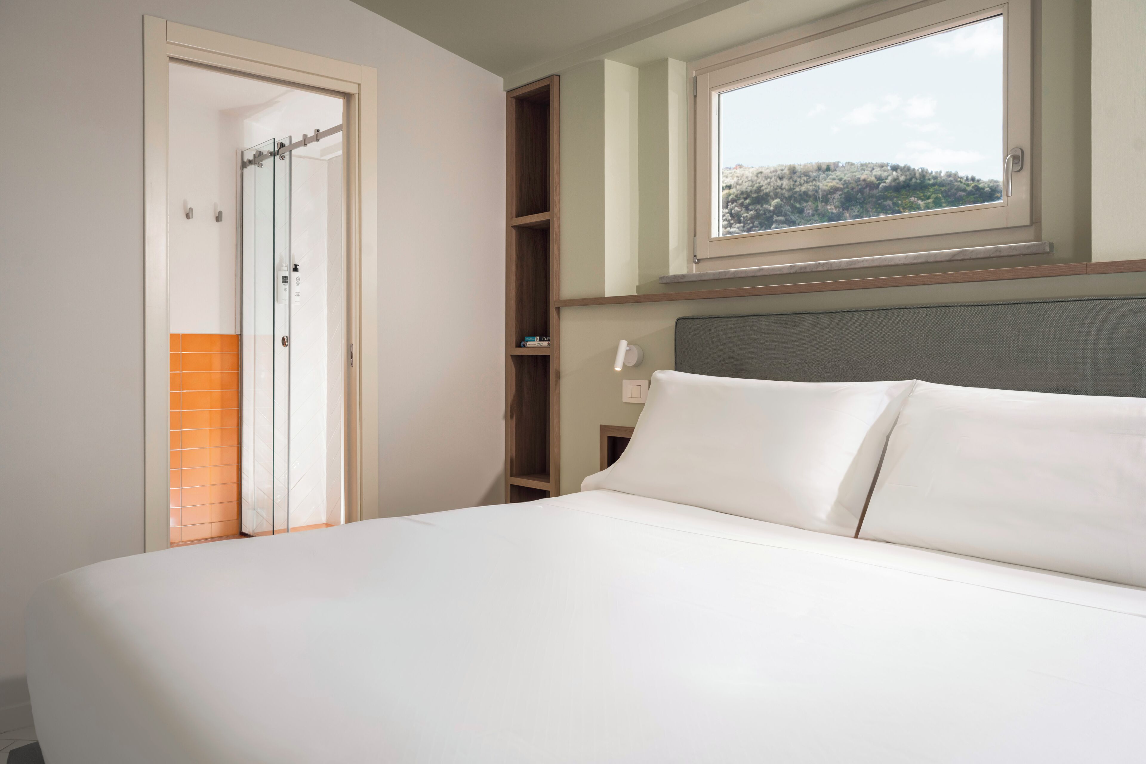 Une chambre à coucher comprenant un lit, une fenêtre, une armoire et une étagère avec des articles de toilette.