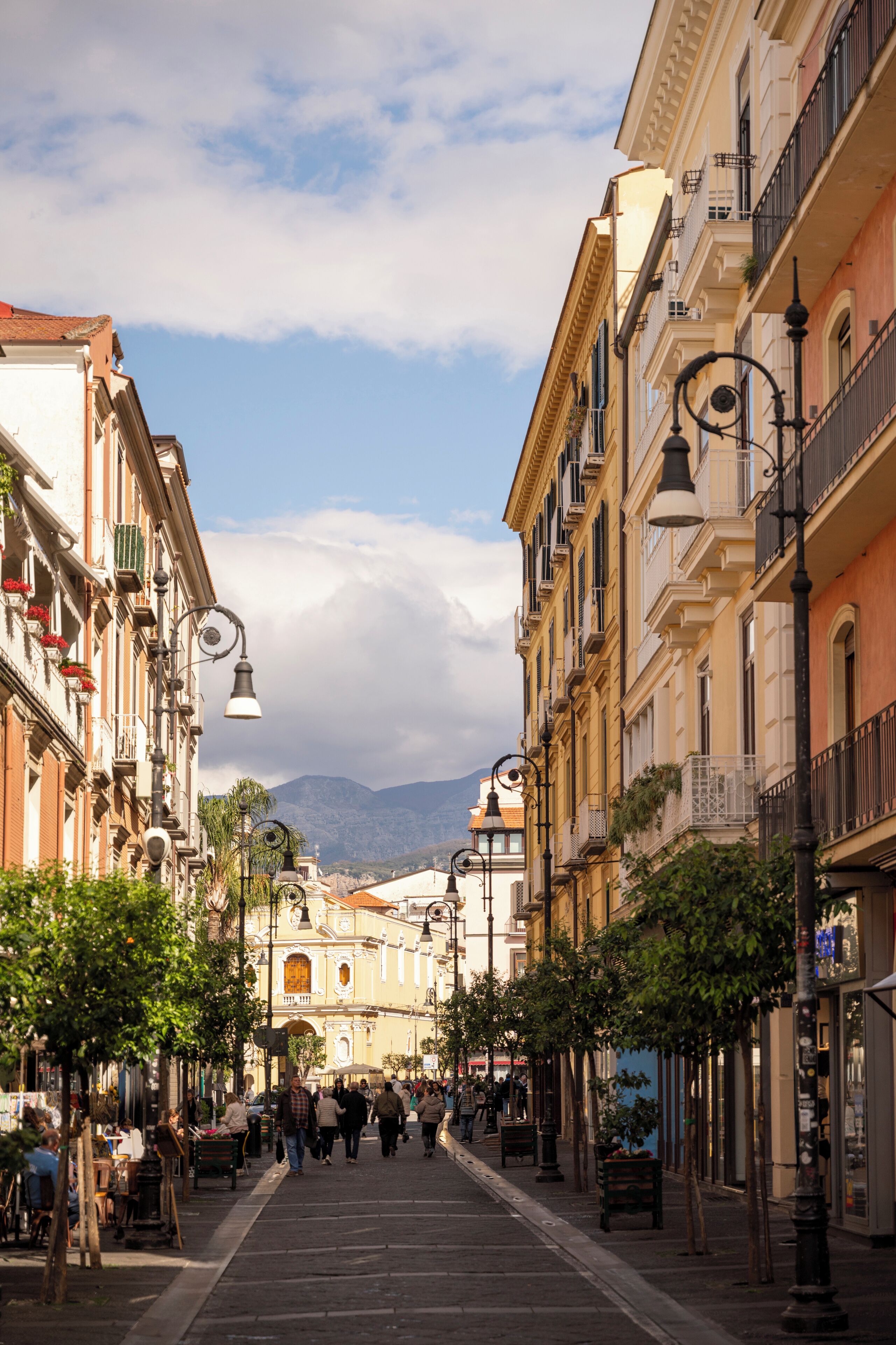 A street lined with historic buildings, a clear sky, and pedestrians.