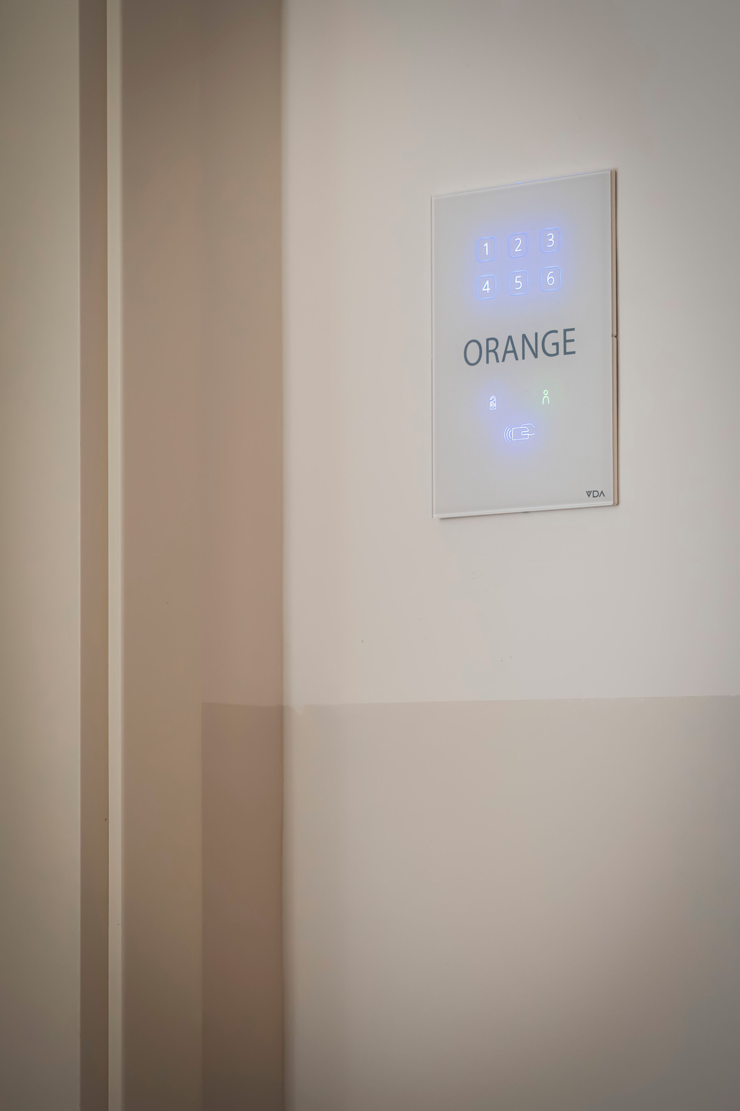 Un teclado electrónico fijado a la pared con la palabra 'ORANGE' y un teclado numérico.