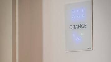 Un teclado electrónico fijado a la pared con la palabra 'ORANGE' y un teclado numérico.