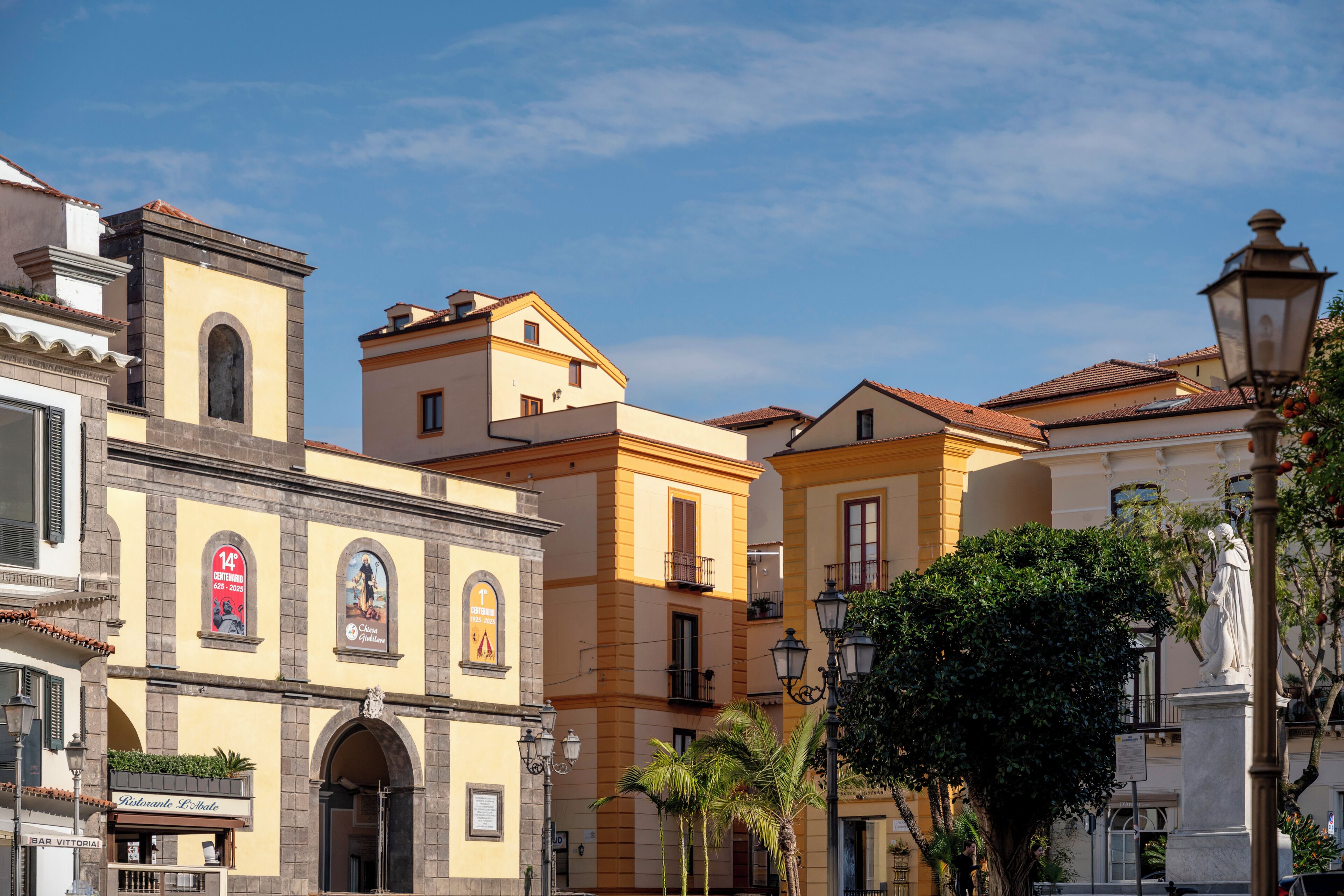 Um edifício histórico com um arco imponente, um letreiro de restaurante e uma estátua.