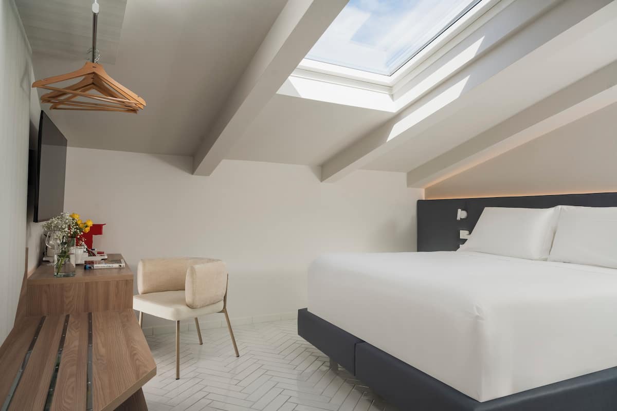 Un dormitorio moderno con tragaluces, una cama, un escritorio y una silla.