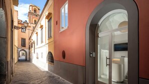 A narrow cobblestone street leading to a building with a large arched entrance and a visible number '33' on the door. - Palazzo Tasso (Sorrento)