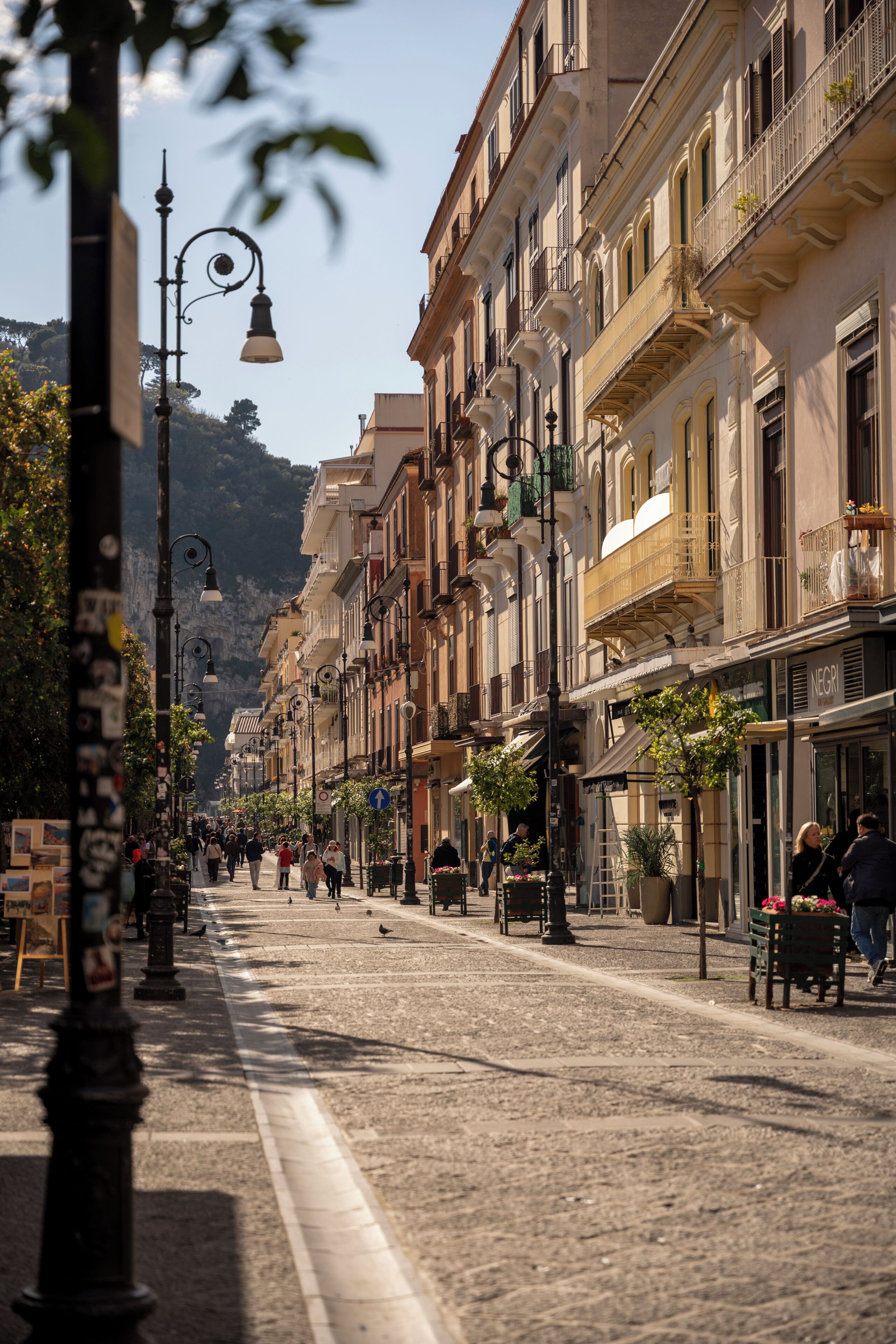 Una calle empedrada flanqueada por edificios históricos, algunos con balcones y terrazas.