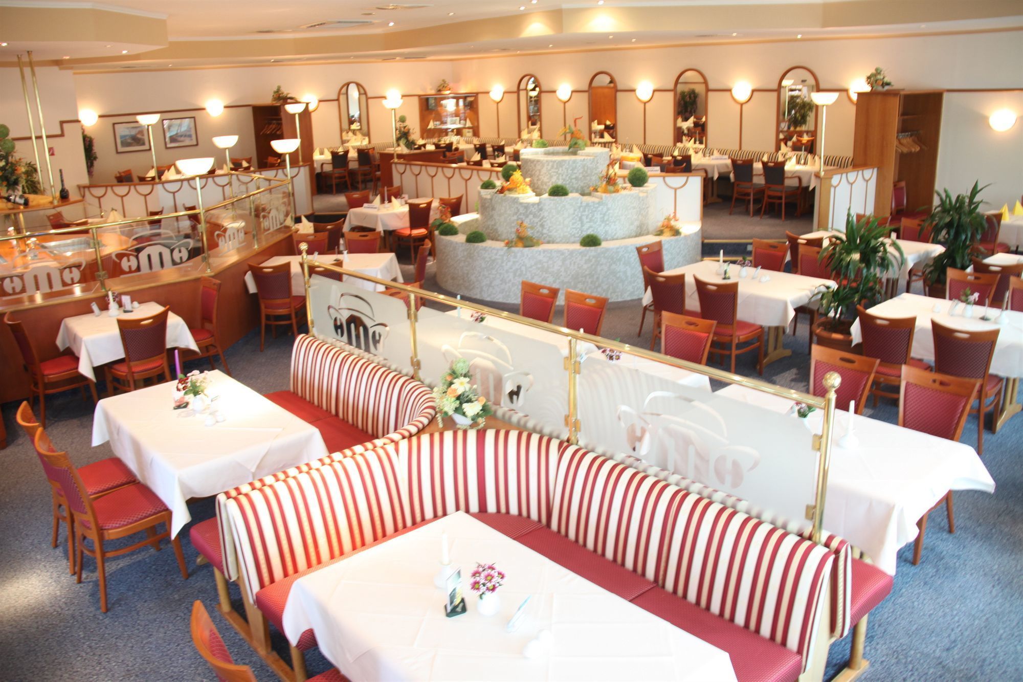 Un restaurante con varias zonas de comedor, incluyendo cabinas y mesas, y una isla decorativa central.