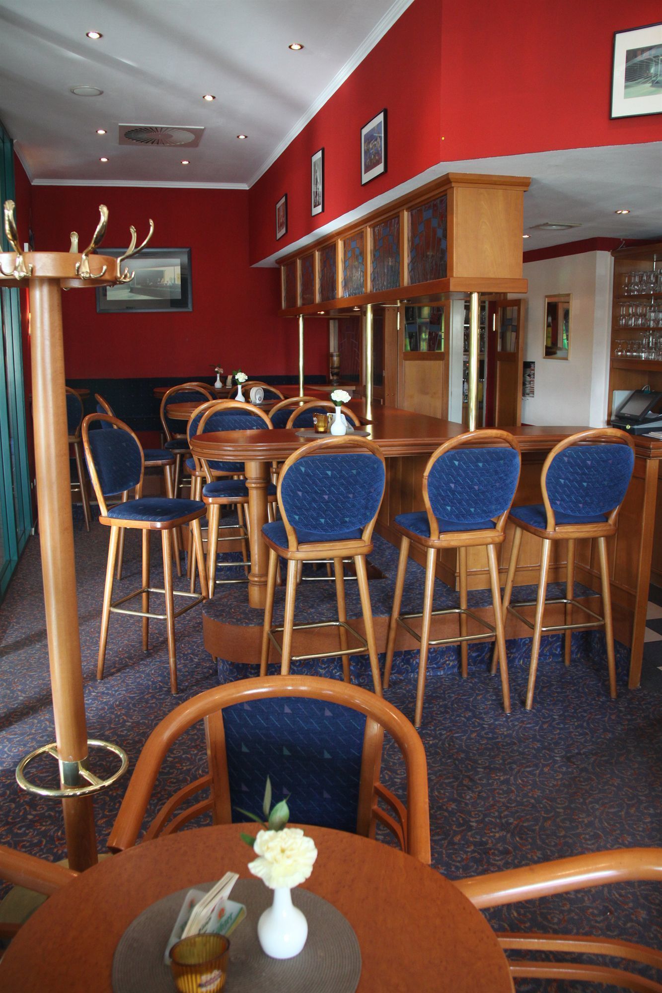 L’intérieur d’un restaurant avec des chaises en bois, un coin bar et des murs rouges.