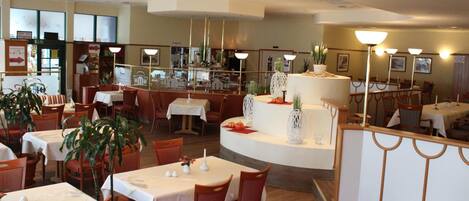 Un restaurante con varias mesas, sillas y una isla decorativa en el centro.