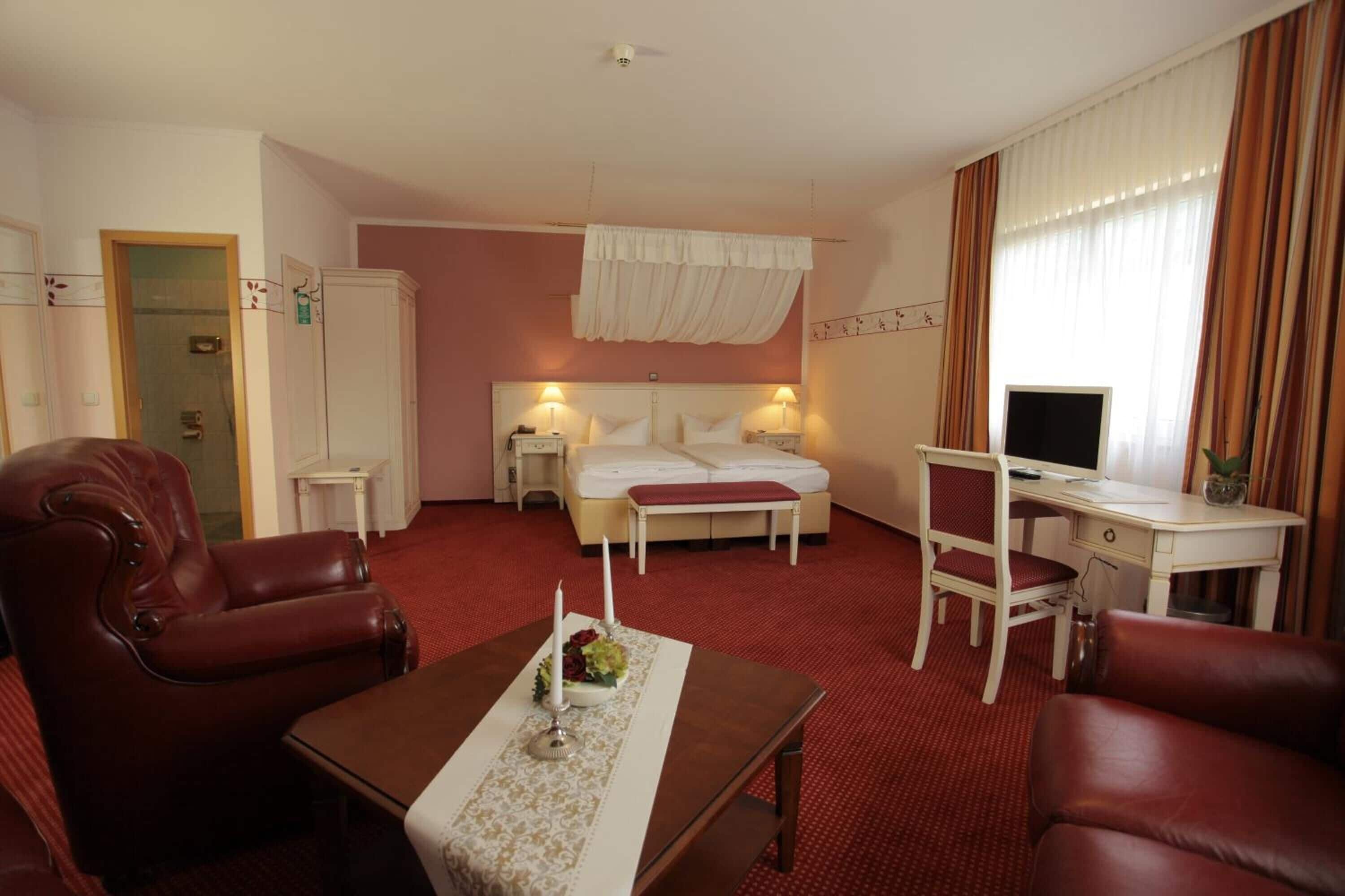 Una habitación de hotel con cama, escritorio, silla, mesa de centro y televisión.