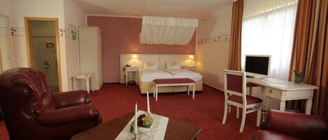 Una habitación de hotel con cama, escritorio, silla, mesa de centro y televisión.