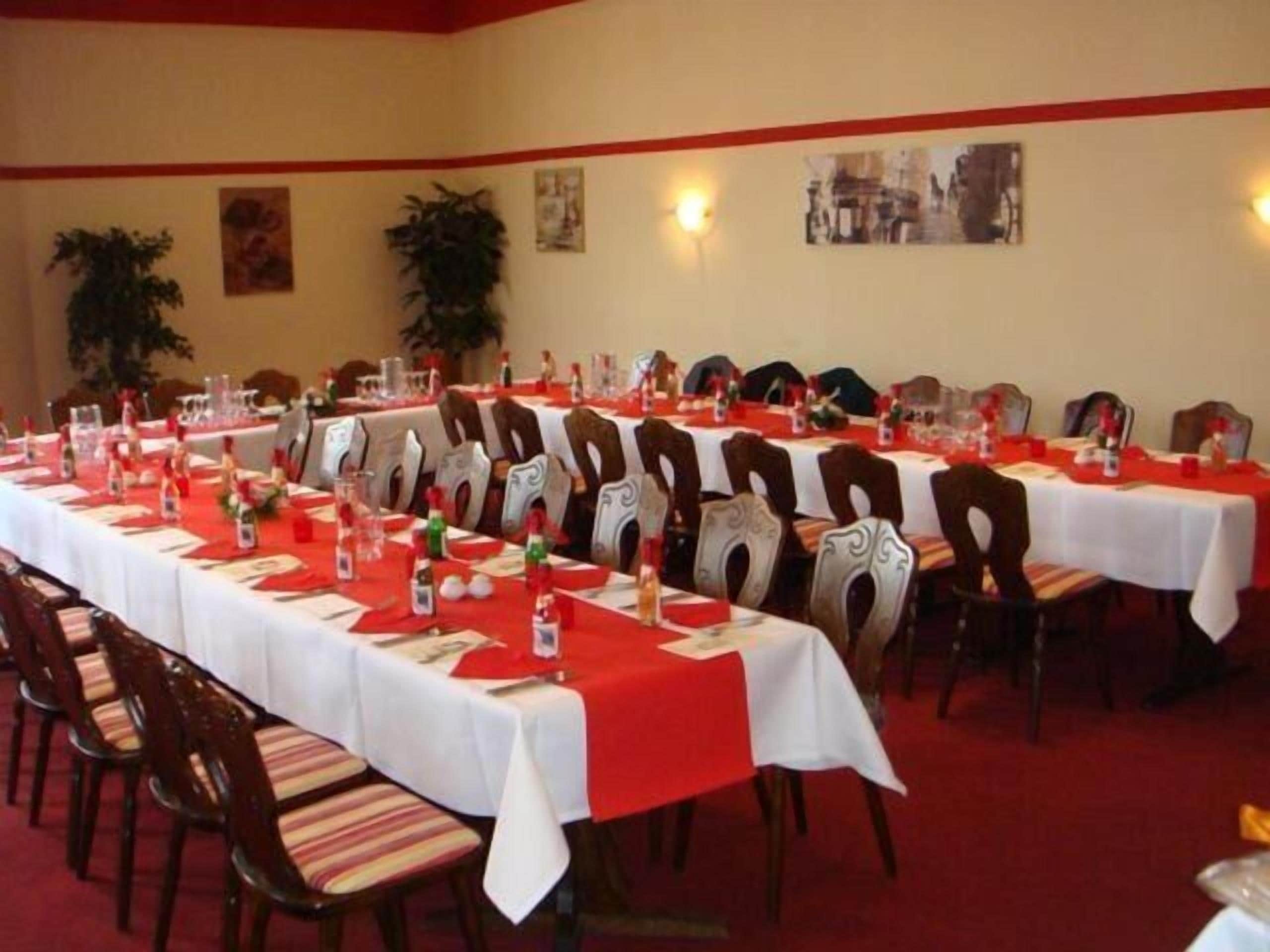 Un salón de conferencias con varias mesas dispuestas para una reunión, equipado con sillas y vajilla.
