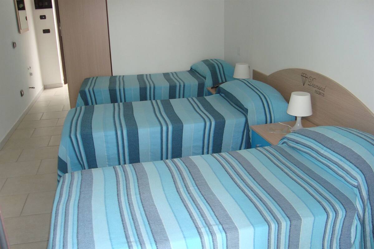 Ein Hotelzimmer mit zwei Betten, jeweils mit gestreifter Bettwäsche, einem hölzernen Kopfteil und einer Nachttischlampe.