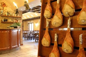 L’intérieur d’un restaurant, avec des viandes rôties suspendues et un bar où sont exposées des bouteilles.