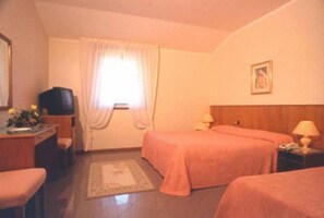 Habitación de hotel con dos camas, un escritorio con televisor y una ventana con cortinas.
