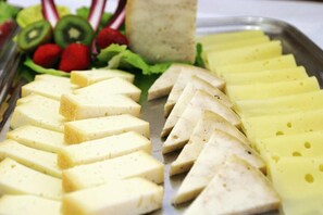 Un plateau de fromages et de fruits coupés en tranches.
