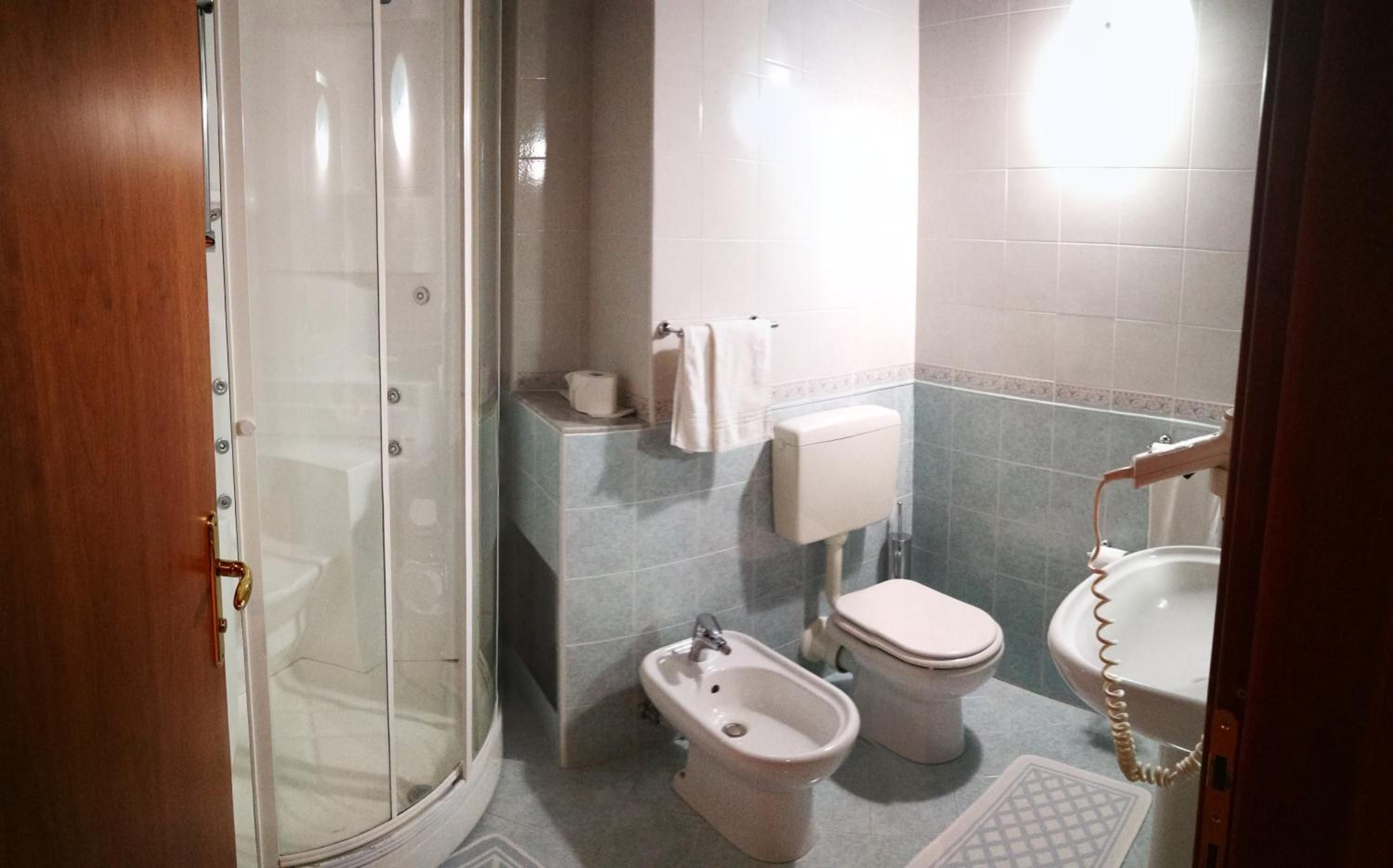 Ein Badezimmer mit Dusche, Toilette, Bidet und Waschbecken.