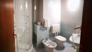 Ein Badezimmer mit Dusche, Toilette, Bidet und Waschbecken.