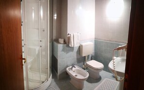 Un baño con ducha, inodoro, bidé y lavamanos.