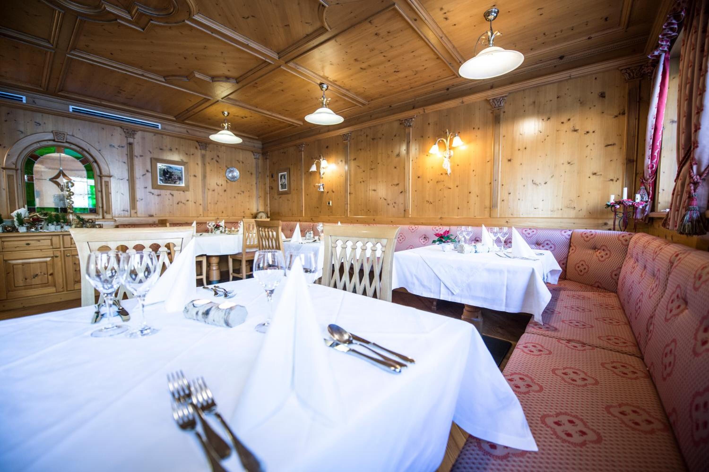 Un restaurant aux murs lambrissés, aux tables blanches et au canapé à motifs.
