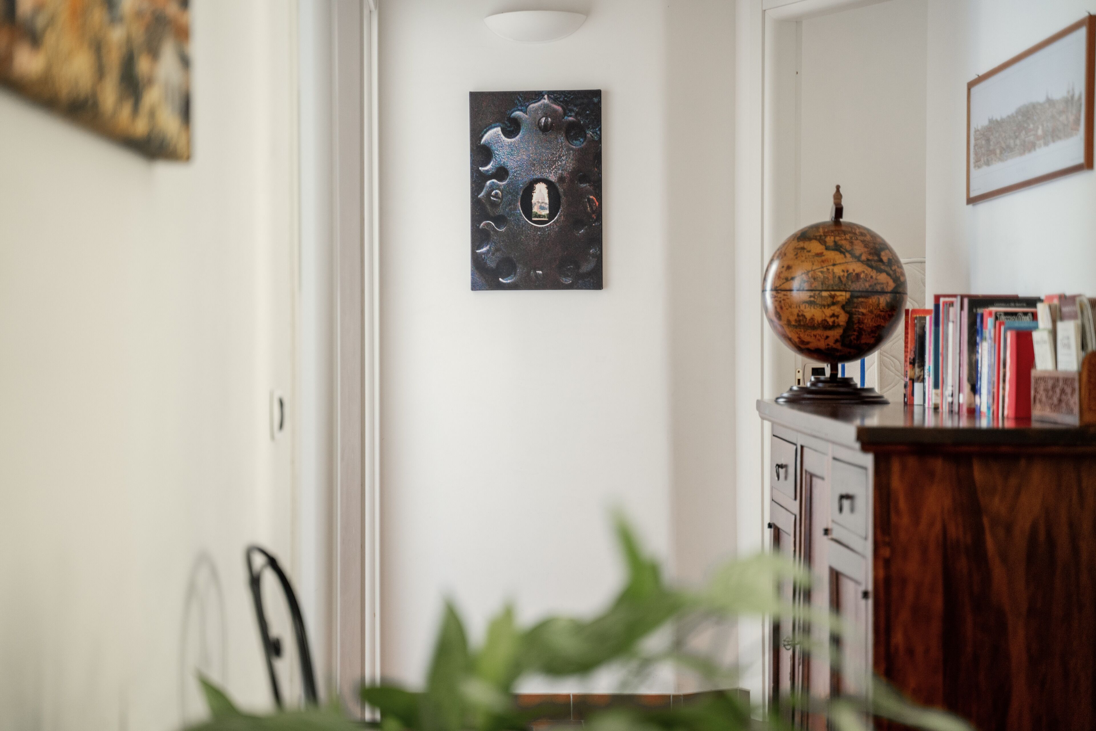 A room with a globe on a wooden cabinet, a door with a metal handle, and a framed picture on the wall.