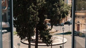 A view of a roundabout with a central fountain, surrounded by trees and a street with parked cars. - Domus Quiritum (Rome)