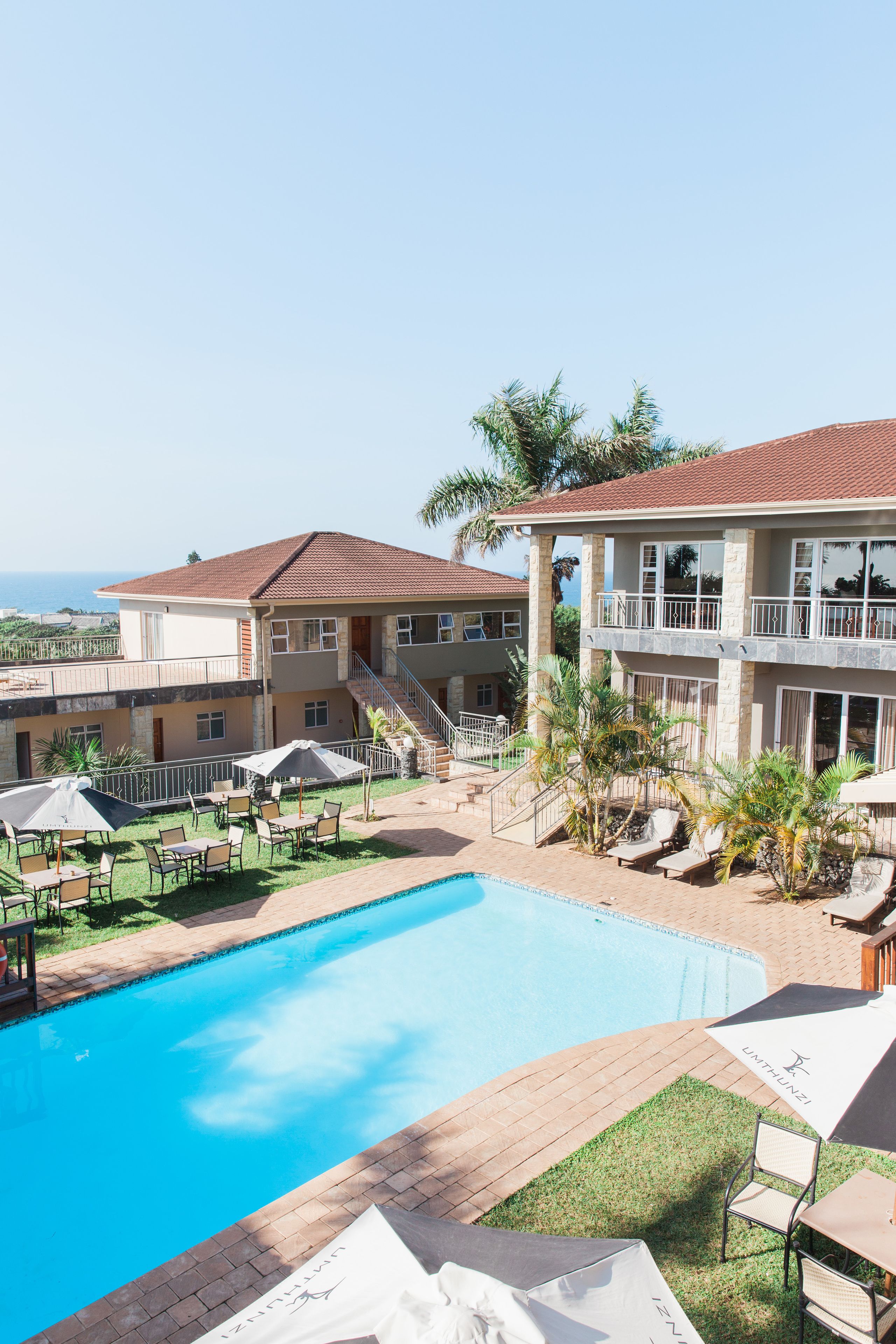 A hotel with a swimming pool, outdoor seating, and a view of the ocean.