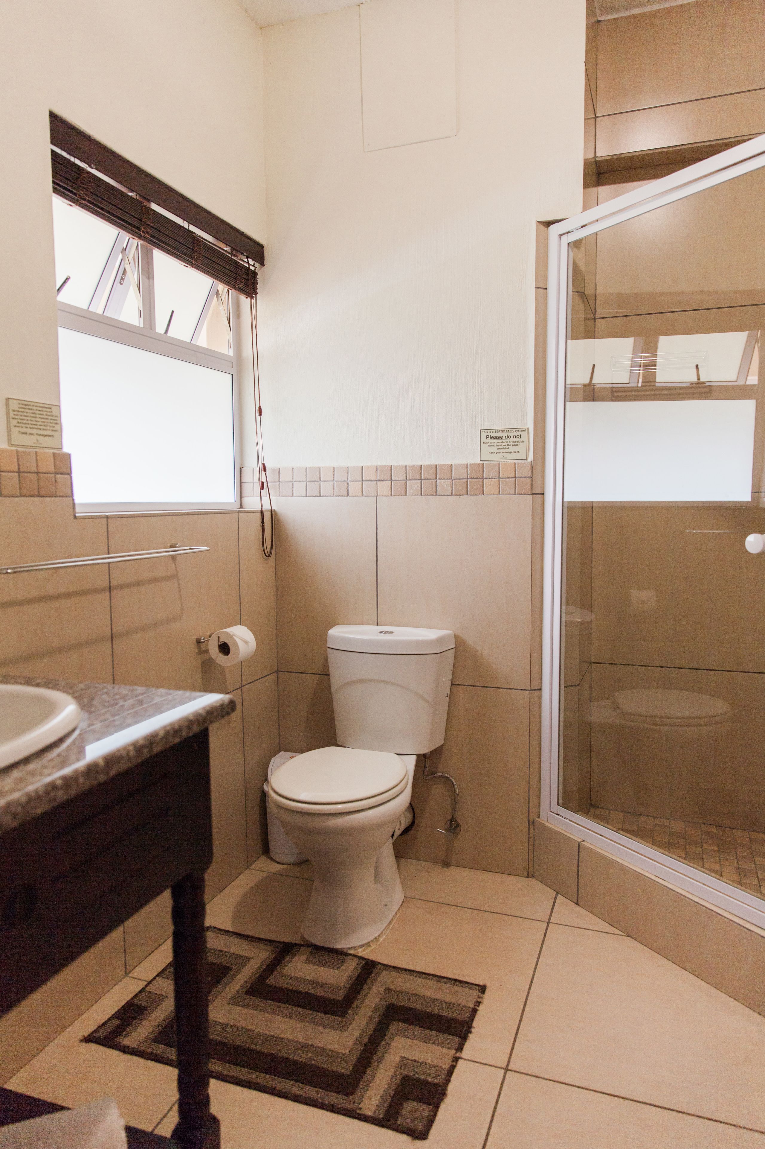 A small bathroom with a toilet, sink, and shower.