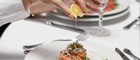 A person squeezing lemon over a dish on a white plate.