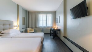 A hotel room with two beds, a desk, a chair, a TV, and a window with curtains. - Smart Hotel King , by R Collection Hotels (Varedo)