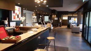 A modern hotel lobby with a reception desk, seating area, and a bar. - Smart Hotel King , by R Collection Hotels (Varedo)