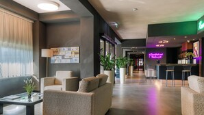 A hotel lobby with a reception desk, seating area, and a restaurant. - Smart Hotel King , by R Collection Hotels (Varedo)