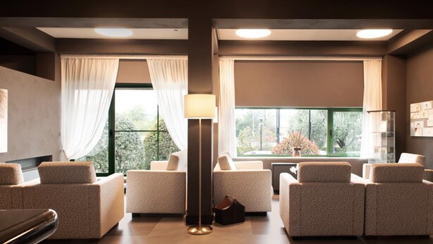 A modern, well-lit room with two sofas, a floor lamp, and a view of greenery outside. - Smart Hotel King , by R Collection Hotels (Varedo)