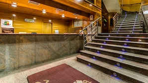 A reception area with a marble counter, a reception desk, and a staircase with blue lighting.