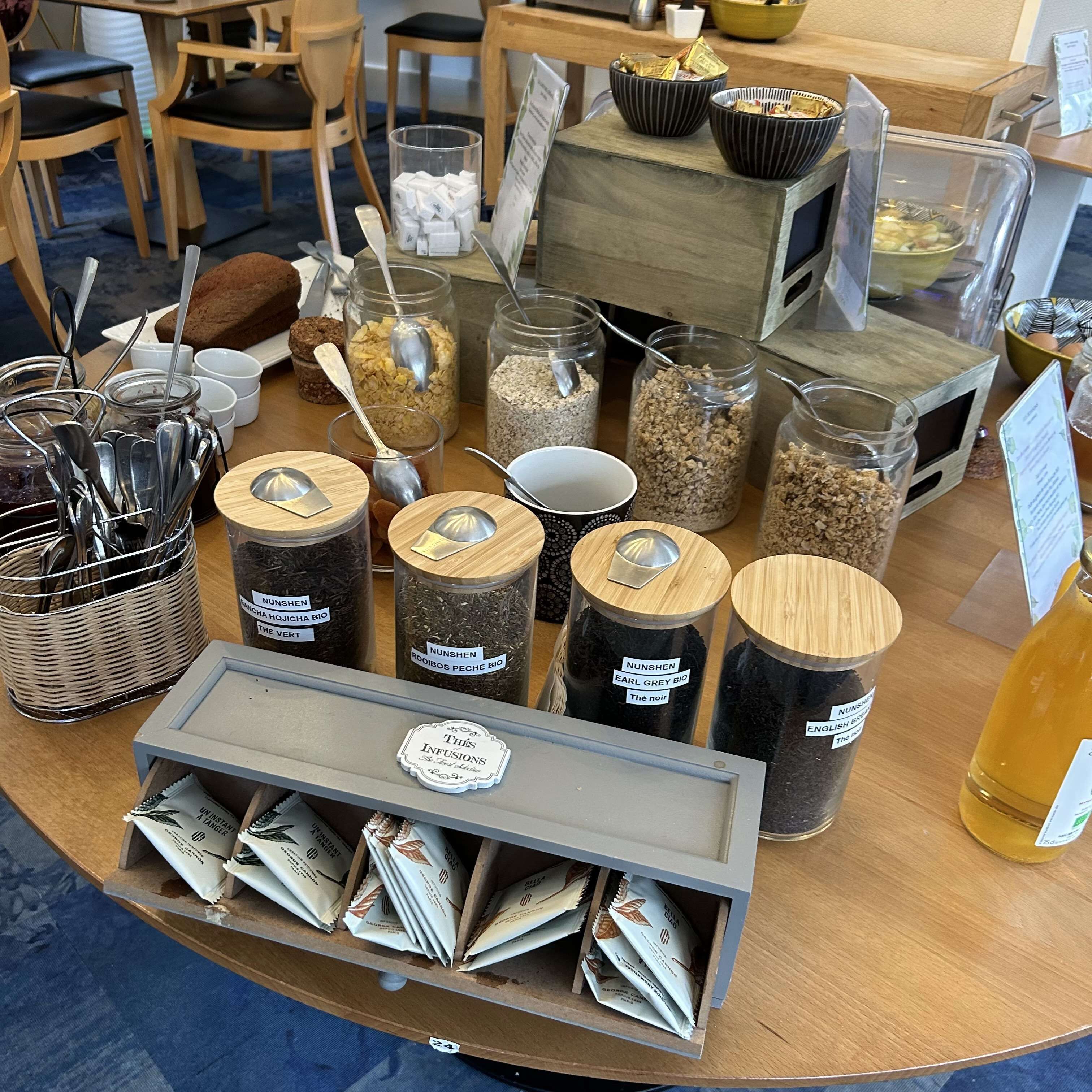 A variety of food items and utensils on a table, including jars of grains and a tray of packaged goods.