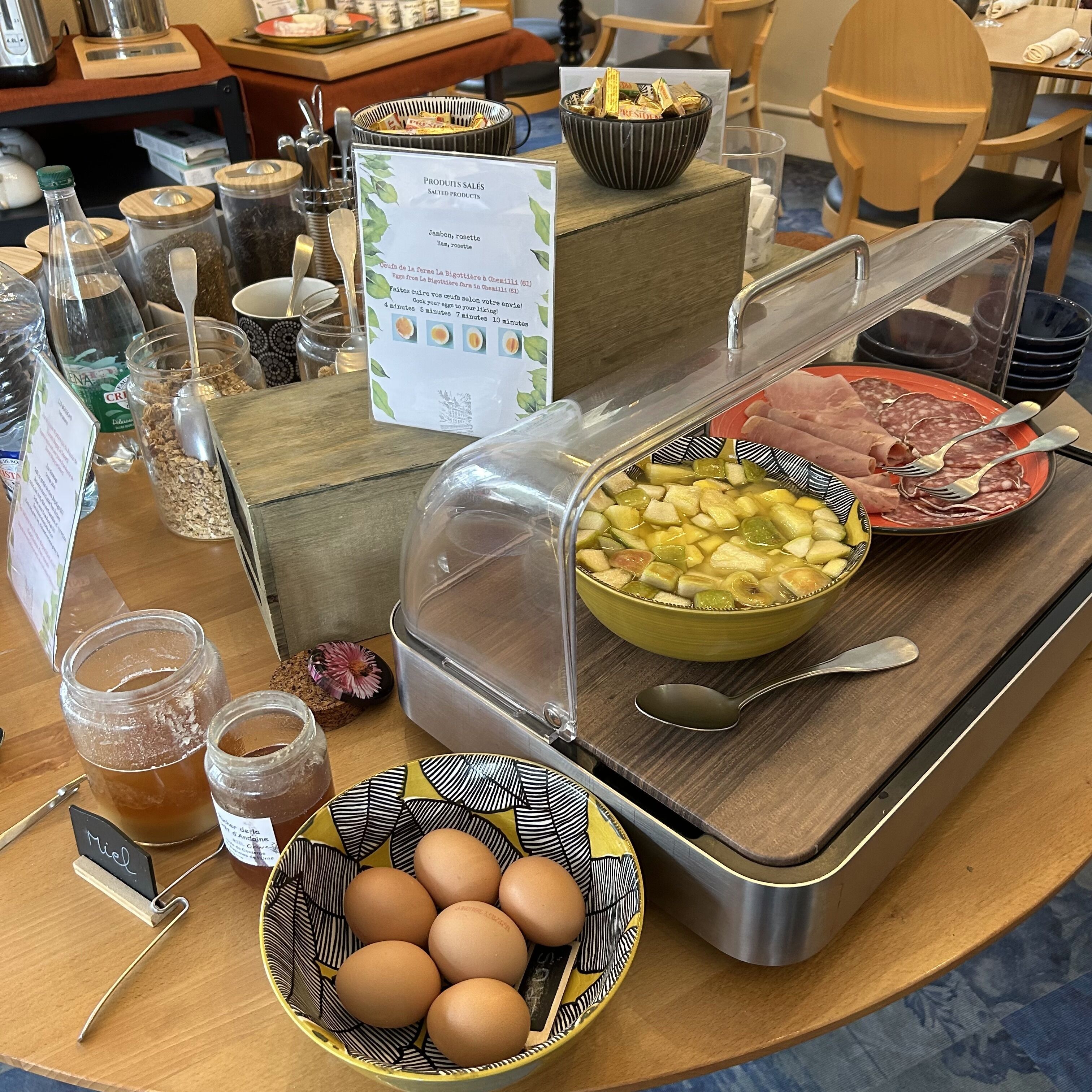 A breakfast buffet with various food items, including eggs, meats, and fruits.