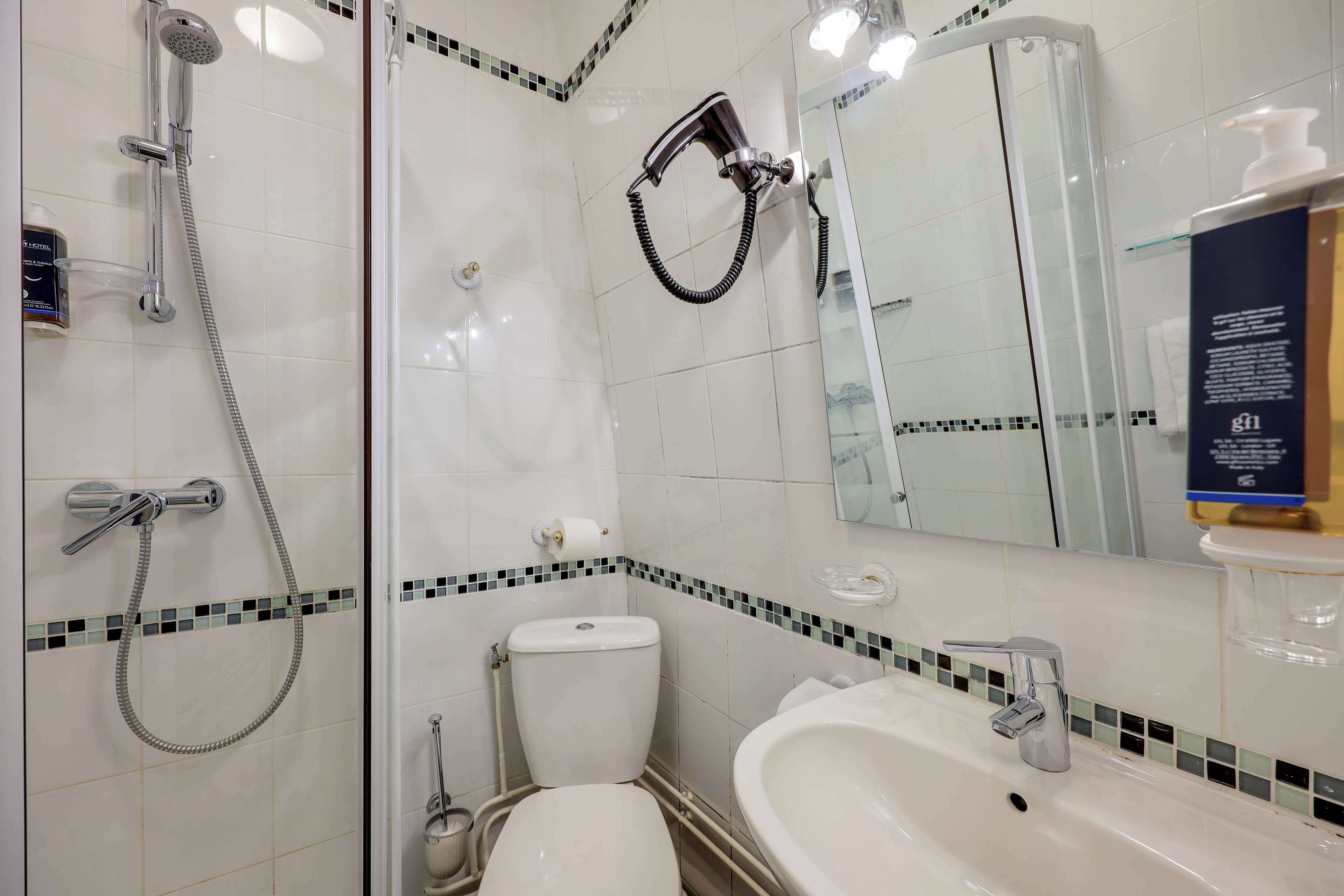 A bathroom with a shower, toilet, sink, and a mirror.