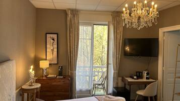 A hotel room with a bed, a desk, a TV, and a balcony with a chair.