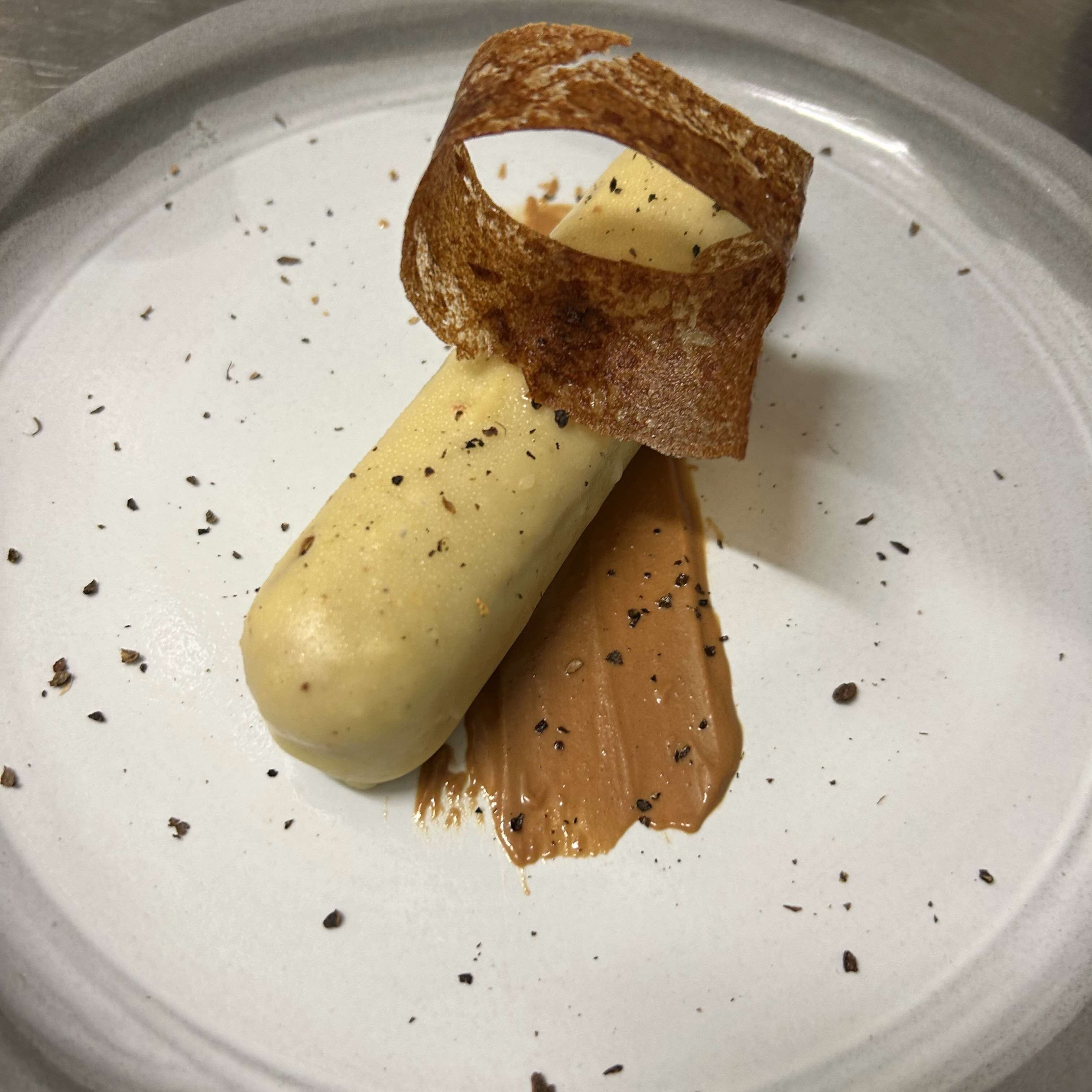 Un dessert servi dans une assiette, accompagné d’une tranche de pain et d’une cuillerée de sauce.