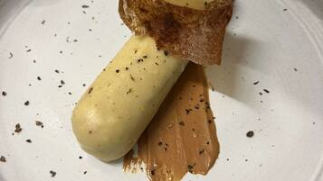 Un dessert servi dans une assiette, accompagné d’une tranche de pain et d’une cuillerée de sauce.