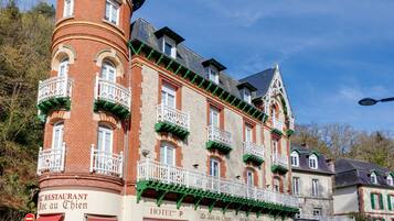 Un hôtel historique doté d’une tour, de nombreux balcons et d’un restaurant appelé « Le Resto au Chien ».