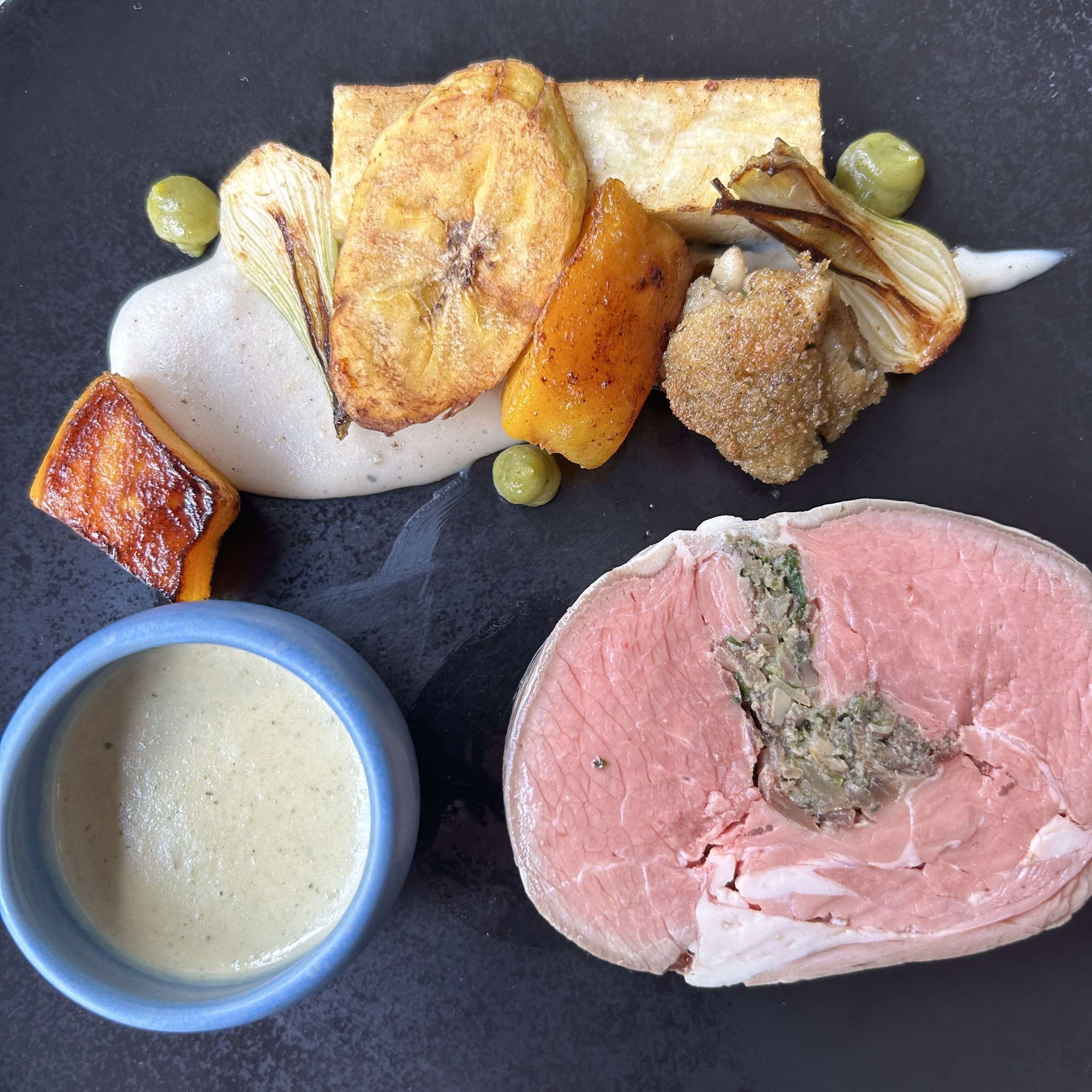 A plate with various food items including a piece of meat, a baked item, and a bowl of soup.