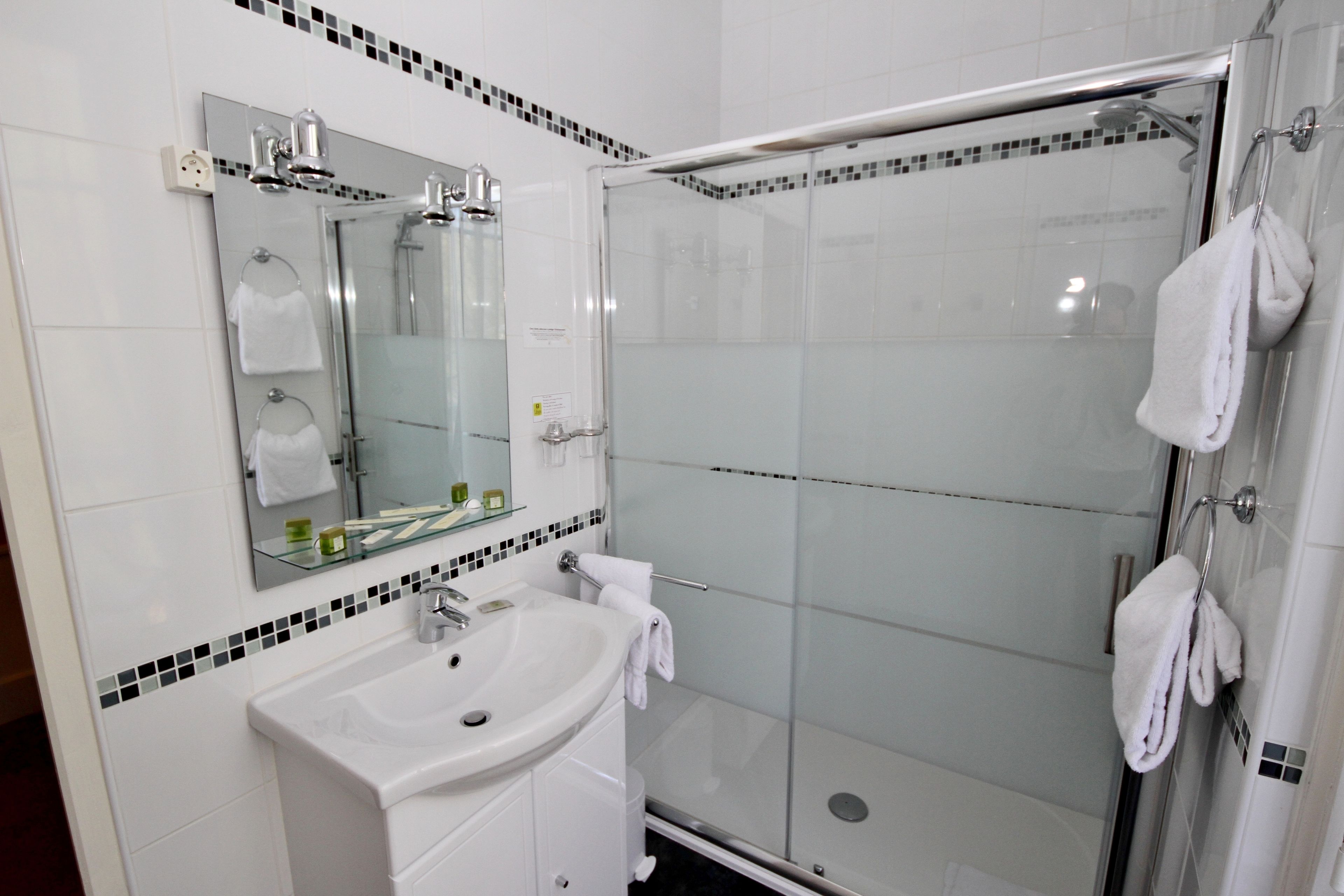 A modern bathroom with a glass-enclosed shower, a white sink, and a mirror above it.