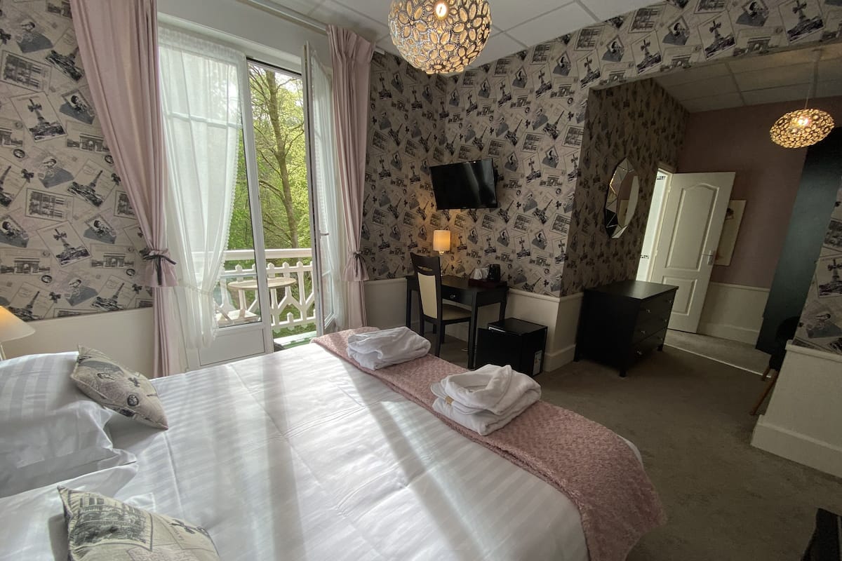 Une chambre d’hôtel avec un grand lit, un bureau, une chaise, une télévision et une armoire.