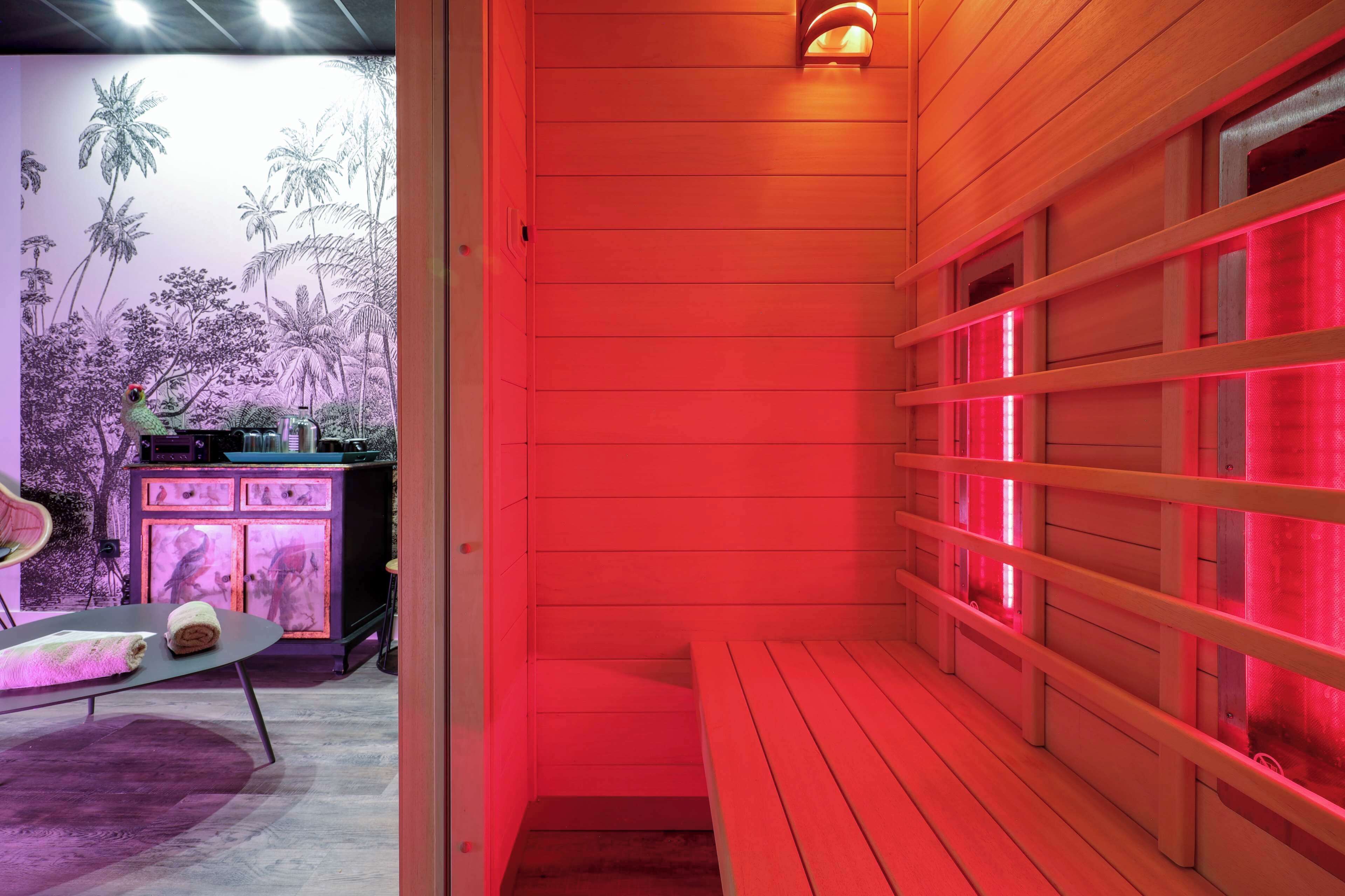 A sauna room with wooden benches and a wall with a tropical mural.